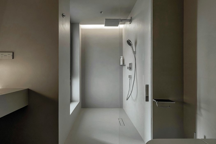 Kupatilo opremljeno u vabi sabi stilu sa jednostavnom tuš kabinom