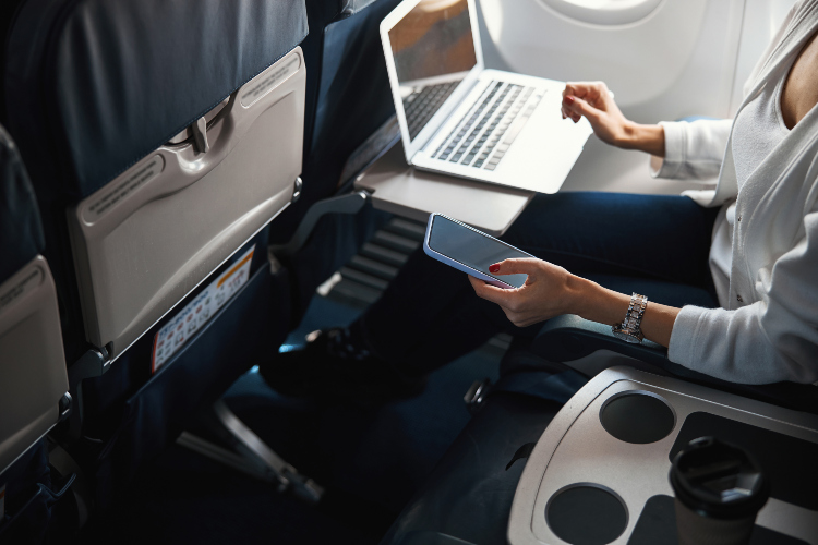 Žena radi na kompjuteru dok udobno sedi u avionu